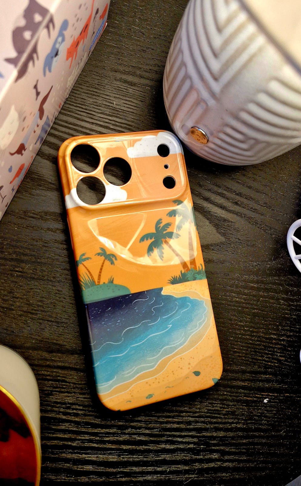 Golden hour beach phone case lifestyle shot on dark wood table