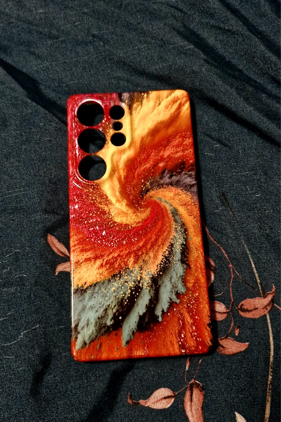Firestorm resin art phone case close-up showing swirl detail on dark fabric